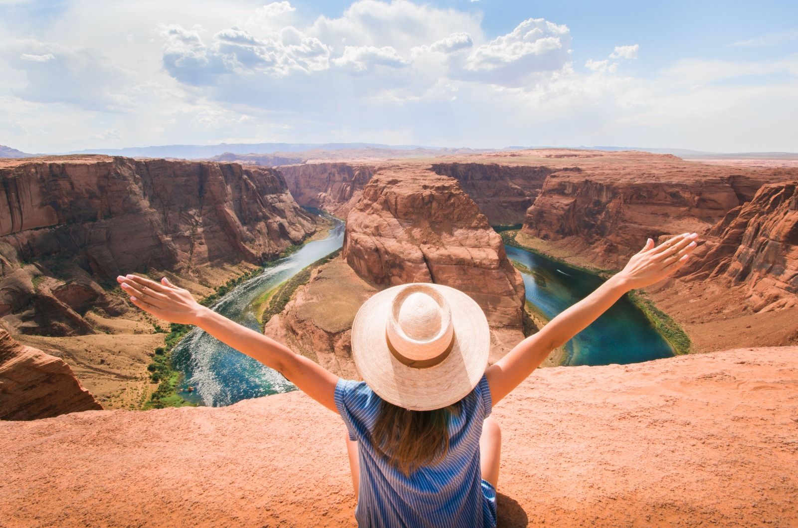 Traveller with arms outstretched above Horseshoe Bend in the USA