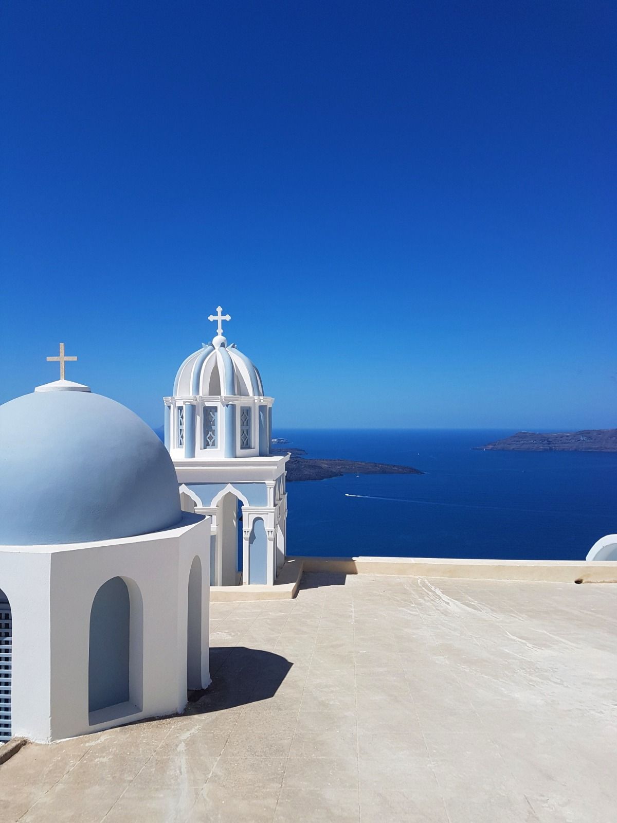 Blue-domed churches overlooking the Aegean Sea in Santorini, Greece