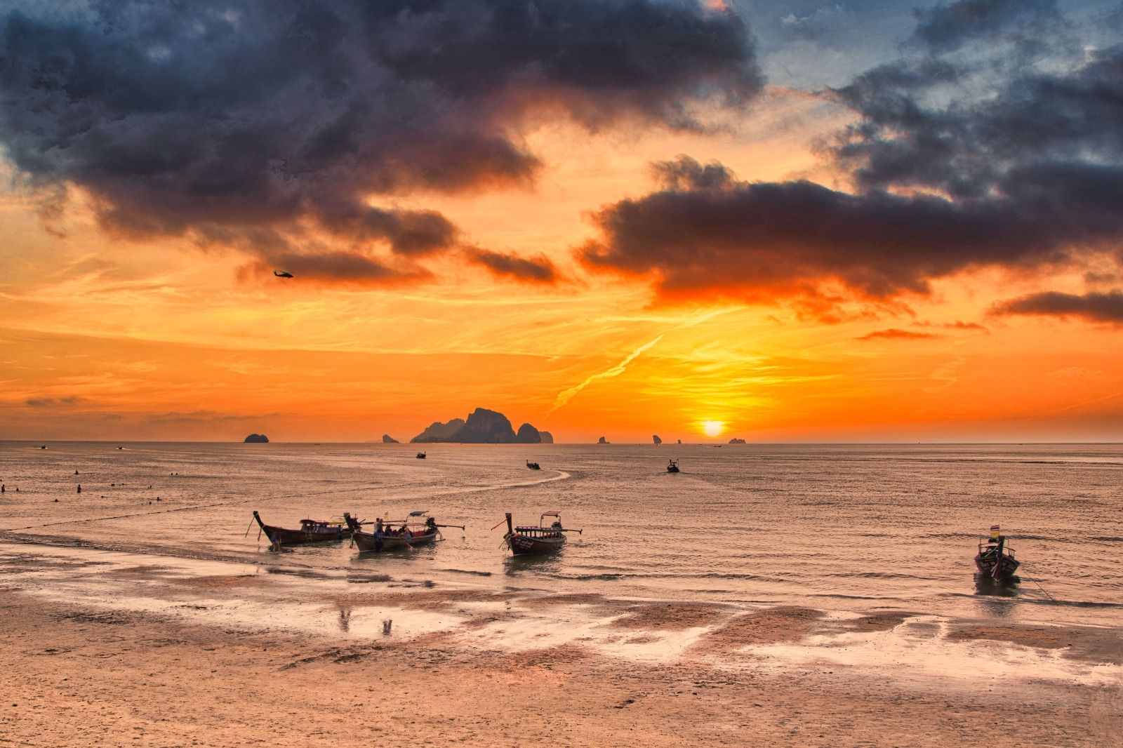 Longtail boats at sunset off a tropical beach